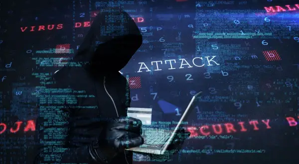 Cyberprzestępca w kapturze planuje ataki hakerskie, używając laptopa i karty kredytowej. W tle widać kod i napisy "VIRUS", "ATTACK", "MALWARE", "SECURITY".