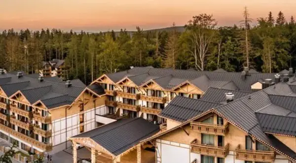 Nowy hotel w górach, oferujący zatrudnienie, otoczony lasem.
