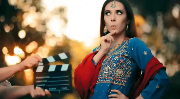 Kobieta w tradycyjnym indyjskim stroju i klaps filmowy na planie.