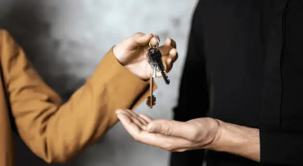 Mani che si scambiano chiavi, simbolo di un immobile in comproprietà abitato da un solo proprietario.