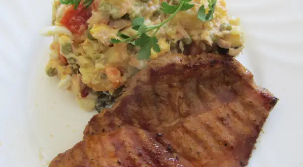 Ein saftiges Schweinefilet mit einem bunten spanischen Salat, garniert mit Petersilie.