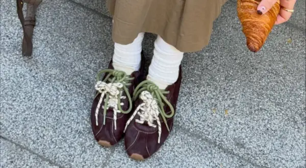 Modne sneakersy 2026 w bordowym kolorze, z zielonymi i białymi sznurówkami, idealne na spacer z croissantem.