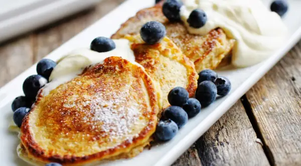 Gyllene pannkakor med havregryn, toppade med vispad grädde och färska blåbär. En härlig frukost eller fika.