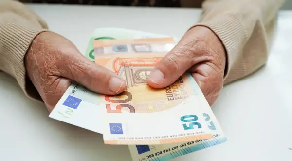 Dłonie trzymają euro. Ile wynosi renta chorobowa w Niemczech po 10 latach pracy?