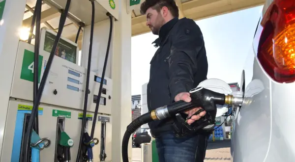 Mężczyzna tankuje benzynę do Skody Fabii 1.2. Dłoń trzyma pistolet paliwowy przy samochodzie.