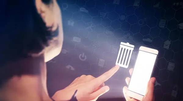 Palec wskazujący dotyka ikony kosza na śmieci, sugerując, jak wyczyścić telefon z niepotrzebnych aplikacji.