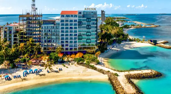 Malediwy w marcu: hotel Arena z widokiem na turkusowe morze i plażę z palmami. W tle budowa i port.