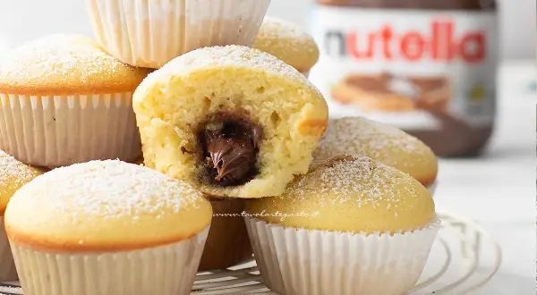Muffin soffici con cuore di Nutella, perfetti per una ricetta muffin semplici e golosa. Spolverati di zucchero a velo.