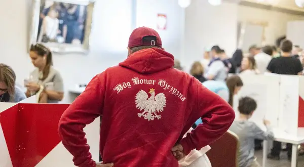 Polacy w UK. Mężczyzna w czerwonej bluzie z orłem i napisem "Bóg Honor Ojczyzna" stoi w tłumie.