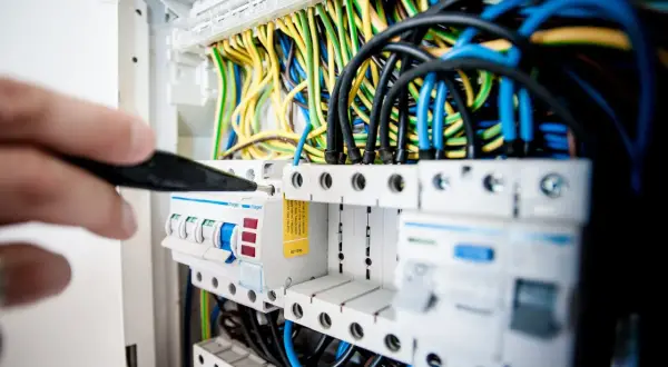 Elektryk sprawdza bezpieczniki w rozdzielni. Może to być związane z problemem: brak jednej fazy w domu.