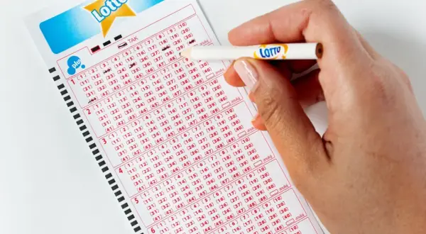 Ręka z ołówkiem zaznacza liczby na kuponie Lotto. Jak poprawnie wypełnić wniosek o loterię wizową DV do USA bez błędów?