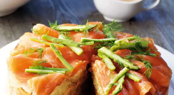 Laxpudding recept: en läcker lax- och potatiskaka toppad med laxskivor, sparris och dill. Perfekt för en festlig måltid.