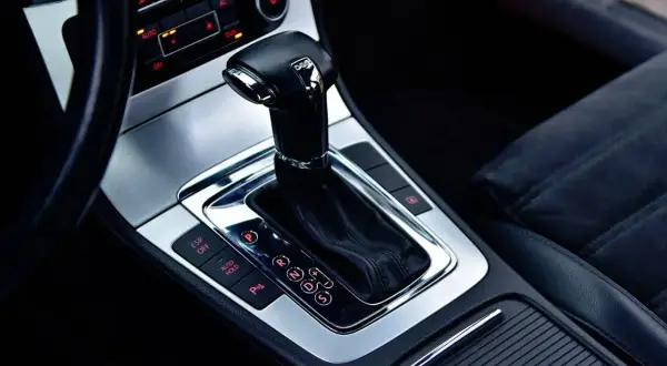 Błyszcząca dźwignia zmiany biegów skrzyni DSG w nowoczesnym samochodzie. Widoczne przyciski ESP, Auto Hold i P.