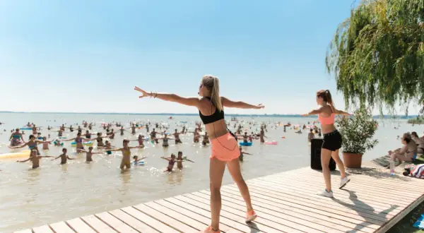 Fitnessgruppe am See in Hévíz, Ungarn. Trainerinnen leiten eine Wassergymnastik-Session für viele Teilnehmer im Wasser.