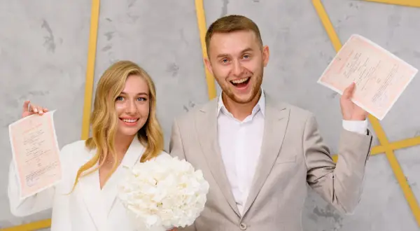 Szczęśliwa para z dokumentami ślubnymi. Czy bierzmowanie jest potrzebne do ślubu? To pytanie nie dotyczy tej radosnej chwili.