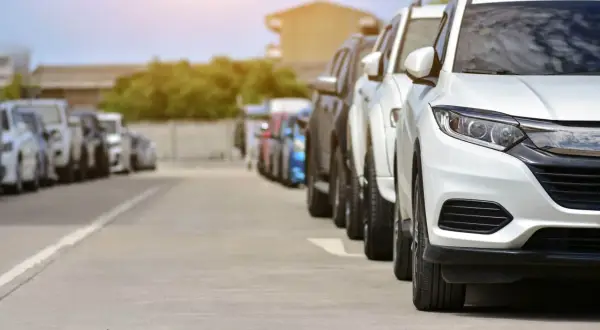 Rząd białych i ciemnych samochodów na parkingu. Może to być scena z transakcji, gdzie nastąpiło zaniżenie wartości samochodu na umowie.