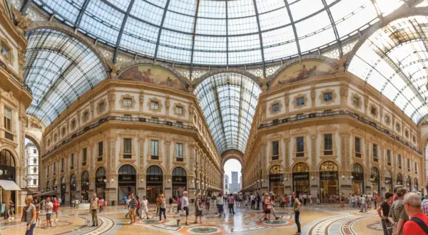 La Galleria Vittorio Emanuele II, un capolavoro architettonico con vetrate luminose e negozi di lusso, accoglie visitatori a Milano.