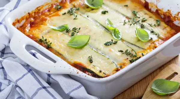 Lasagne courgette gratinée, dorée et savoureuse, garnie de feuilles de basilic frais et de thym. Un délice léger et réconfortant.