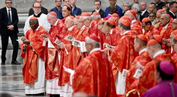 Kardynałowie w czerwonych szatach, przygotowujący się do wyboru papieża, trzymają w rękach dokumenty.