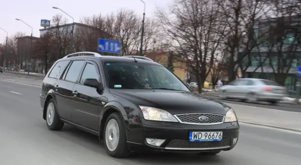 Czarny Ford Mondeo MK2 kombi jedzie ulicą.