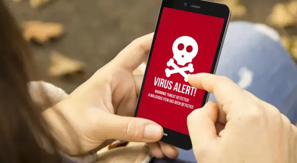 Osoba wykonuje skanowanie telefonu, gdy na ekranie pojawia się czerwony komunikat "VIRUS ALERT!".