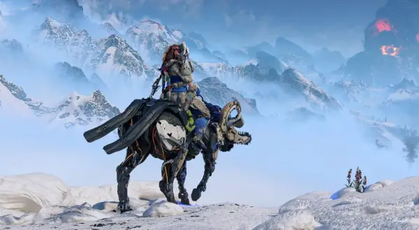 Aloy na mechanicznym koniu przemierza śnieżne góry. W oddali widać wybuch wulkanu, zapowiadający zagrożenie w Horizon 3 Nemesis.