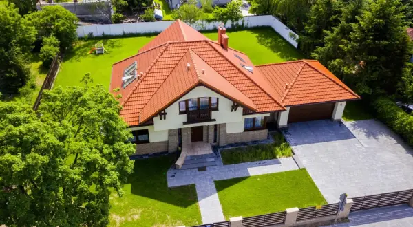 Piękny dom z czerwonym dachem i ogrodem. Zastanawiasz się, ile kosztuje projekt domu?
