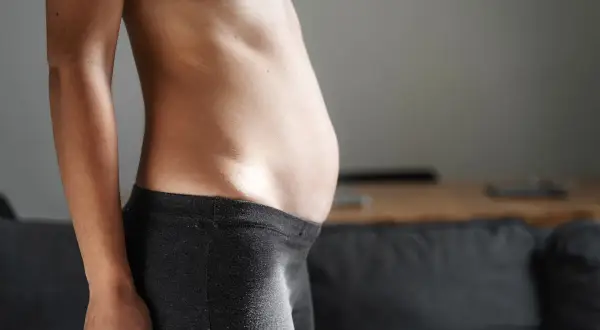 Profilo di una donna con addome prominente, possibile segno di diastasi addominale.