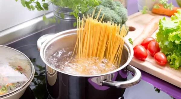 Spaghetti kochen in sprudelndem Wasser. Daneben frisches Gemüse wie Brokkoli, Karotten und Tomaten. So einfach ist es, wie koche ich nudeln!