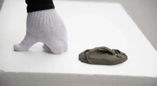Ręka w rękawicy przygotowuje masę do wylewki na styropianie. Kluczowe jest, ile styropianu pod wylewkę zostanie użyte.