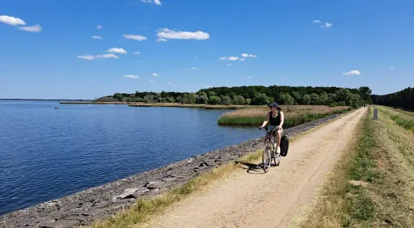 Kobieta na rowerze przemierza malownicze trasy rowerowe opolskie wzdłuż jeziora.