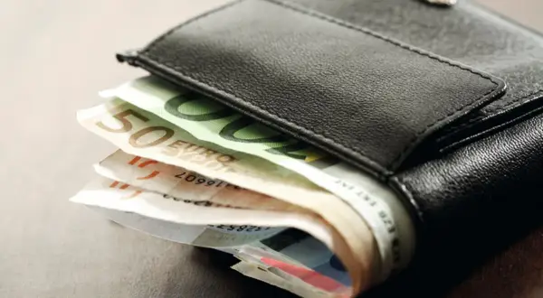 Schwarzes Lederportemonnaie mit Euro-Scheinen. Die Scheine deuten auf die Gehaltszahlung nach dem tarifvertrag wohnungswirtschaft eingruppierung hin.