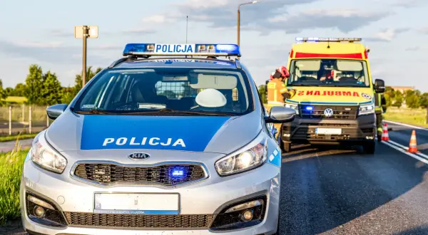 Radiowóz policyjny i karetka na poboczu drogi w Emilianowie. Służby zabezpieczają miejsce zdarzenia.
