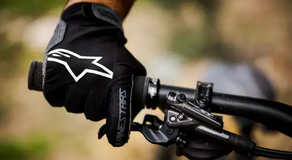Mano enguantada con logo Alpinestars en manillar de bici. ¡Ya me duermen las manos en la bici!