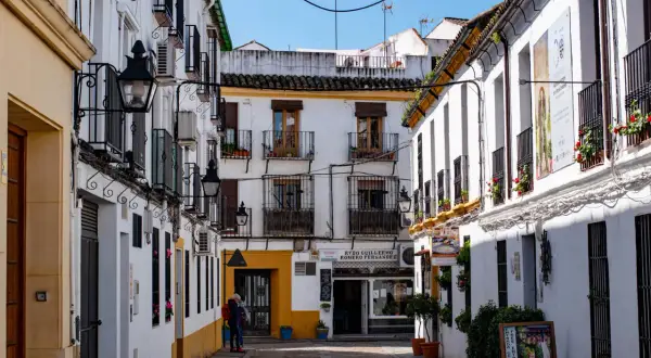 Callejuela cordobesa con casas blancas, balcones de hierro y faroles. Un cartel anuncia "Entrada Gratuita", ideal para saber qué ver en Córdoba gratis.