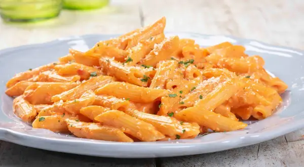 Penne cremose con salsa rosa, un'idea per primi piatti sfiziosi. Spolverata di parmigiano e prezzemolo fresco.