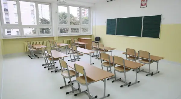 Pusta sala lekcyjna z ławkami i krzesłami, jakby czekająca na uczniów, kiedy wprowadzono gimnazjum w Polsce.