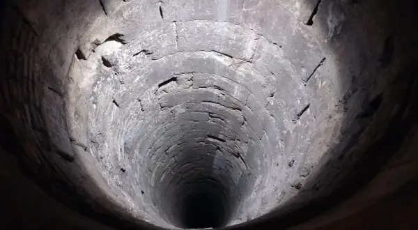 Blick in einen alten, steinernen Brunnen. Die Wände sind rau und uneben, was auf die Notwendigkeit hinweist, den Brunnen abzudichten.