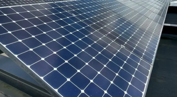 Panele fotowoltaiczne na dachu, które mogą zasilać piec elektryczny do podłogówki, odbijają niebo.