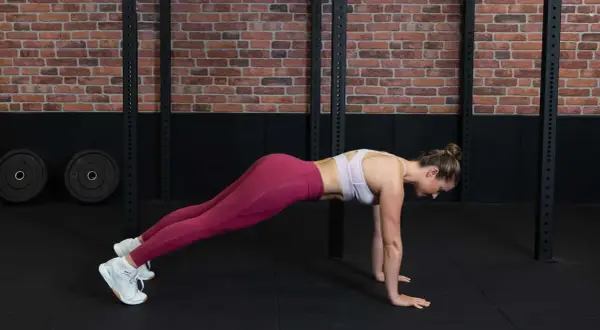 Frau in einem Fitnessstudio macht eine Plank-Übung für ihr **core training**.