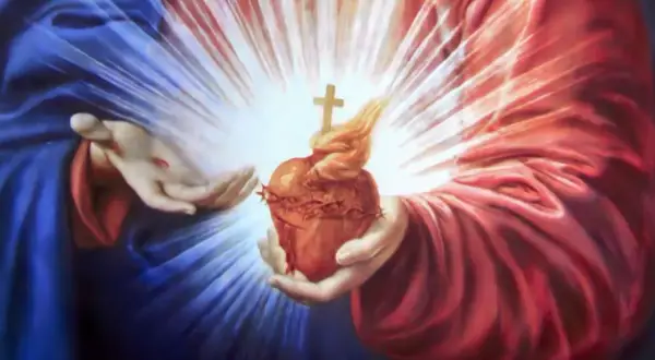 Dłonie trzymają gorejące Serce Jezusa, symbol miłości i drogi do rozwoju duchowego.