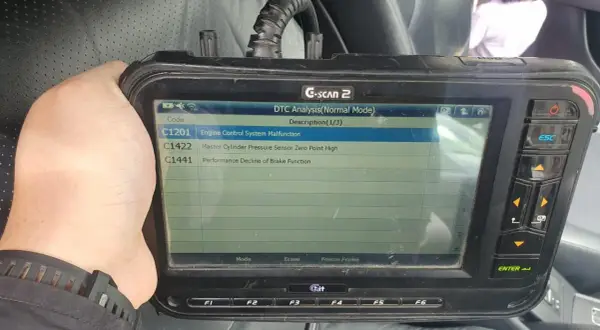Escáner G-SCAN 2 muestra código C1201, fallo en sistema de control de motor de un Toyota.
