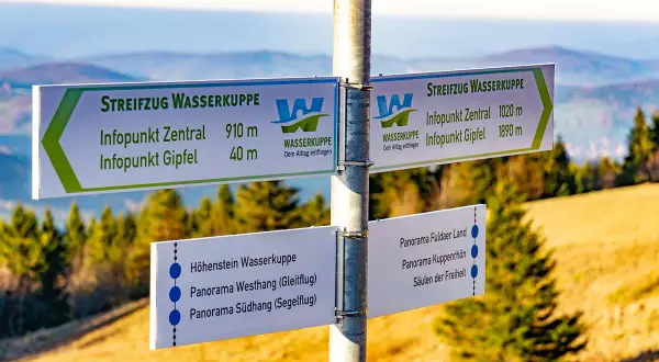 Wegweiser am Gipfel der Wasserkuppe für Wanderer. Hier beginnt der Streifzug Wasserkuppe, mit Zielen wie Infopunkt Zentral und Gipfel.
