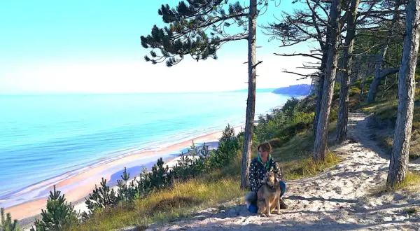 Frau mit Hund auf einem sandigen Pfad mit Blick auf die polnische Ostsee.