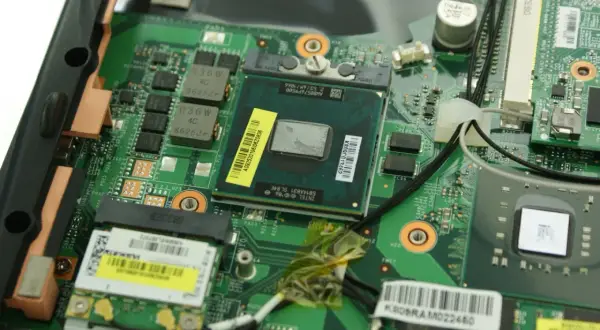 Nahaufnahme eines geöffneten Laptops, bereit für den **laptop cpu wechseln**. Der Prozessor ist sichtbar, umgeben von grüner Platine und Kabeln.