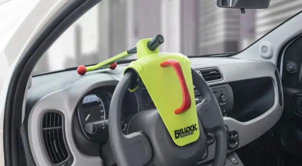 Un antivol de volant Bullock Defender est installé. Il est jaune vif avec une poignée rouge. Il n'y a pas de clé visible, ce qui peut faire penser à comment débloquer un volant sans clé.