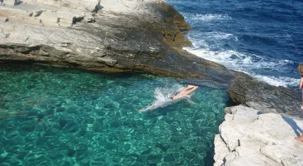 Niesamowite thassos atrakcje: krystalicznie czysta woda w naturalnym basenie skalnym, w którym pływa osoba.