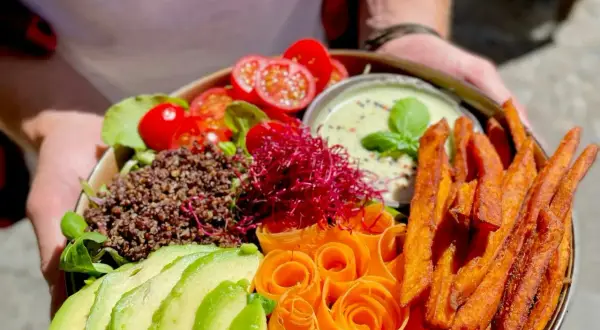 Ein farbenfroher Buddha Bowl mit Quinoa, Avocado, Karottenrosen, Süßkartoffel-Pommes und einem cremigen Dip. So schmeckt froindlichst Berlin!