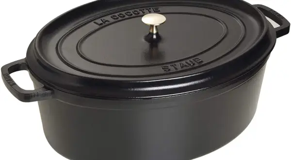 Schwarzer ovaler Schmortopf von Staub mit goldfarbenem Griff. Perfekt für langsam gegarte Gerichte, was ein Schmortopf eben ist.