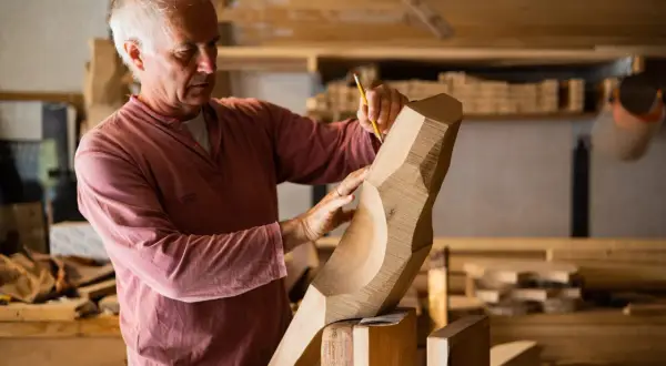 Saverio Pastor, scultore del legno, con matita e mani esperte definisce le forme di un'opera in lavorazione.
